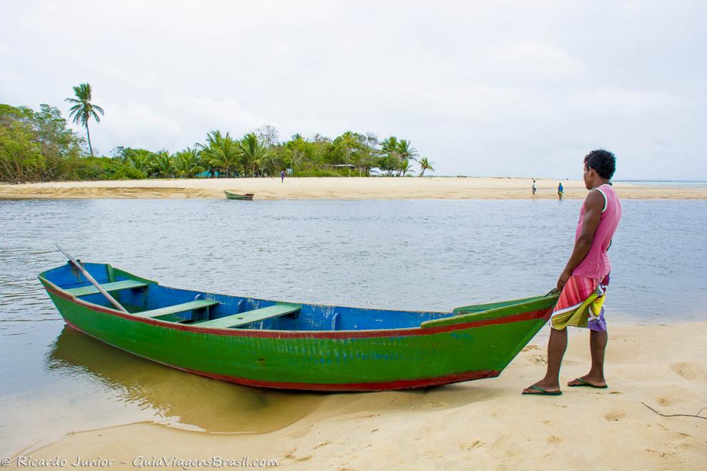 Imagem de um pescador na frente de seu barco na Praia de Corumbau.